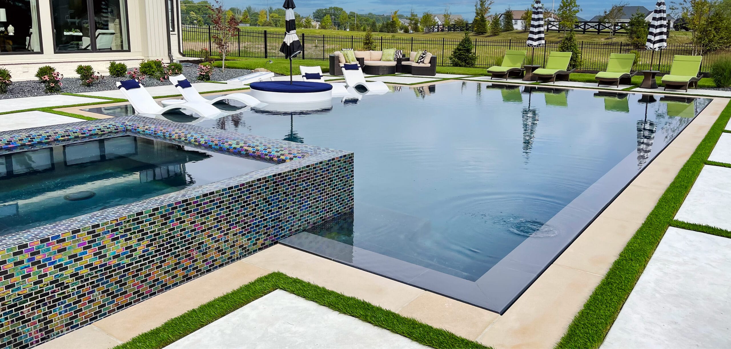 Full-perimeter overflow pool with glass-tiled rim-flow spa..