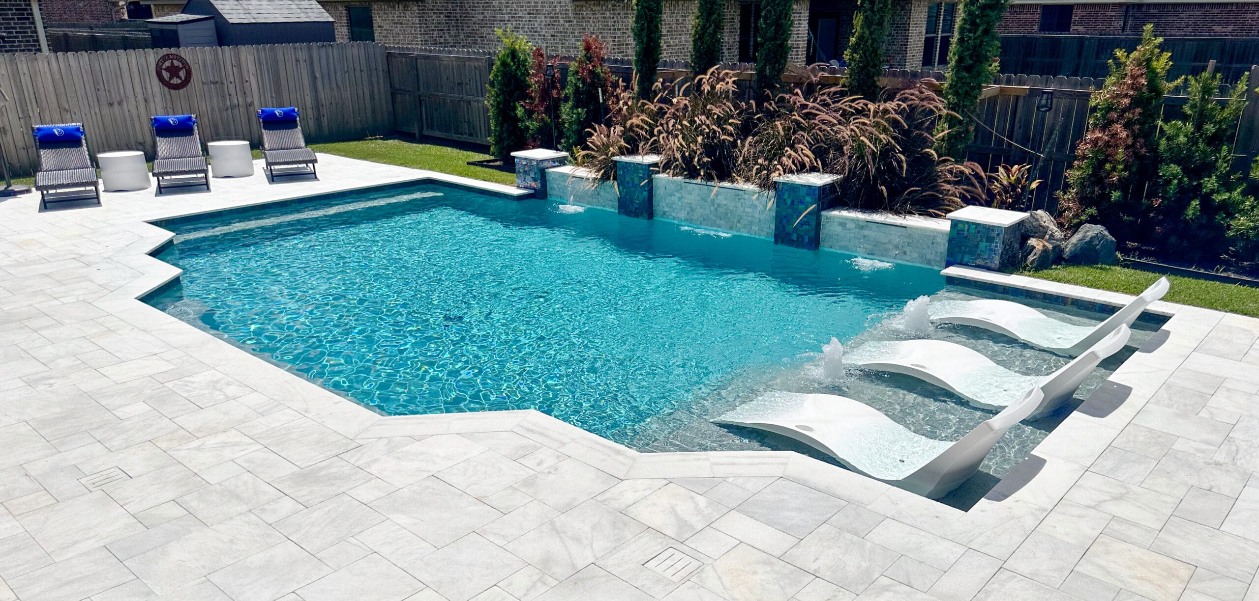 Modern backyard pool with large tanning ledge and cascade water features.