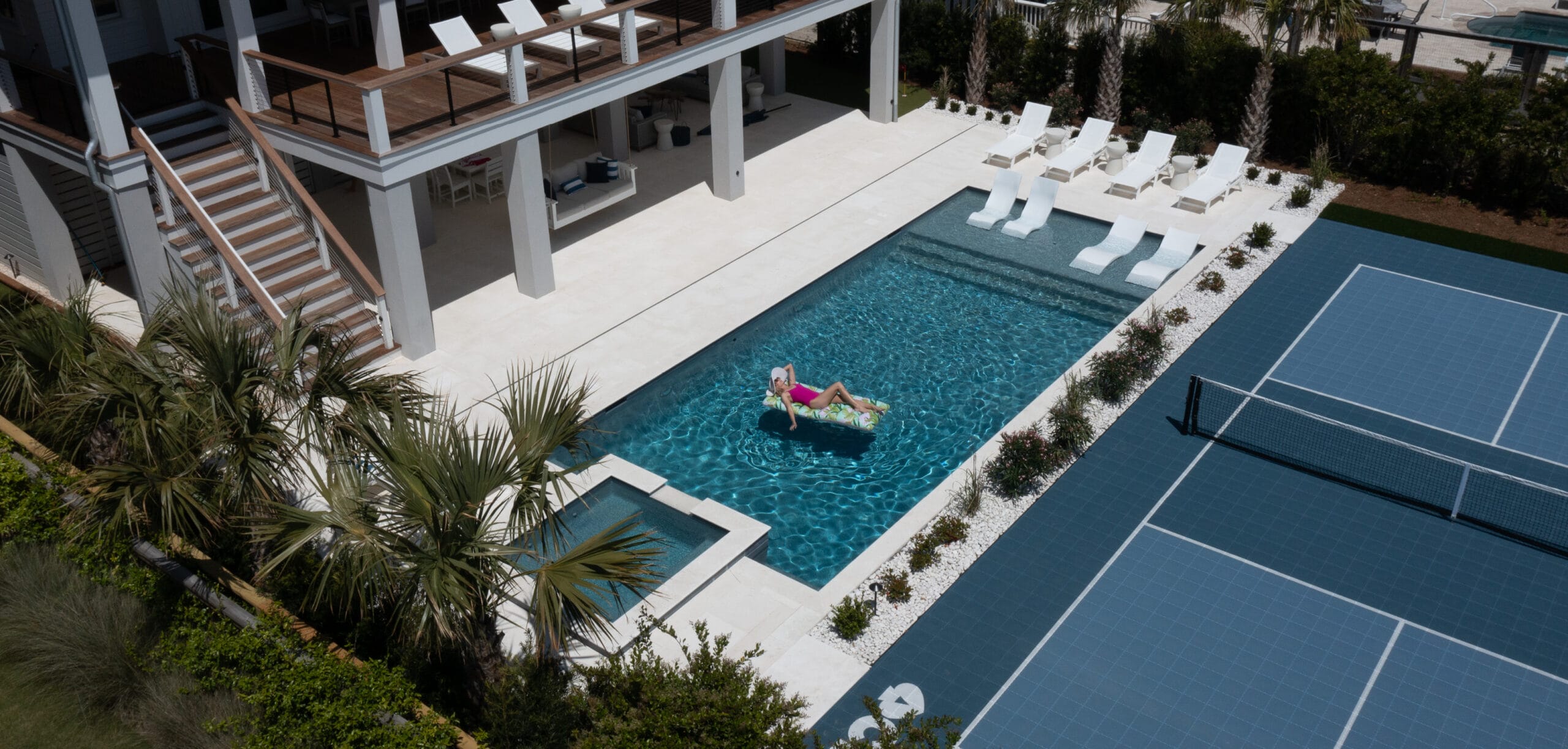 Backyard pool with woman in lounging on float in the pool water. 